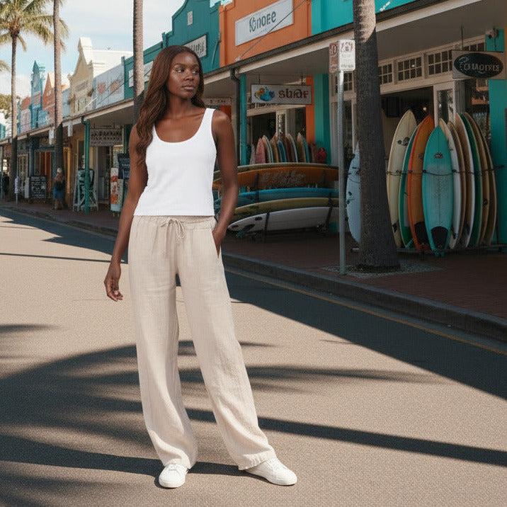Person wearing beige wide-leg pants and white sneakers on a plain background