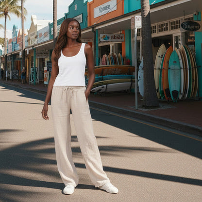 Person wearing beige wide-leg pants and white sneakers on a plain background